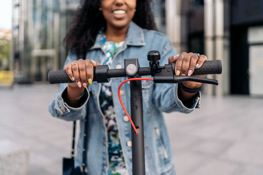 En Hyvel se vende la pila para scooter eléctrico, hay una mujer que está arriba de un scooter