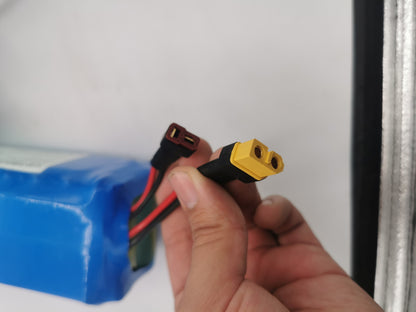 Una mano sosteniendo los cables conectores de la Batería Externa para Scooter 48V 9Ah con los cables saliendo de la parte superior